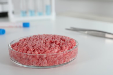 Photo of Petri dish with raw minced cultured meat on white table in laboratory, closeup