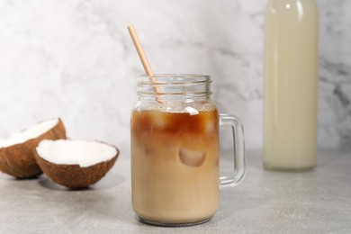 Photo of Mason jar of delicious iced coffee with coconut syrup on light grey table