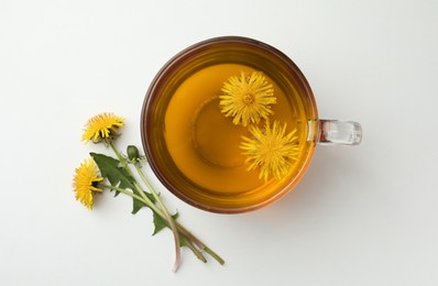 Delicious fresh tea and dandelion flowers on white background, top view