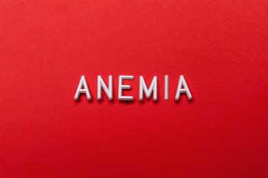 Photo of Word Anemia on red background, flat lay
