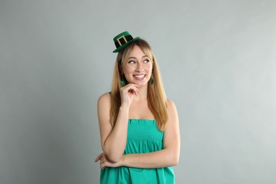 Happy woman in St Patrick's Day outfit on light grey background