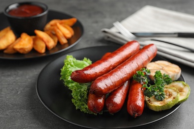 Delicious grilled sausages and vegetables on grey table