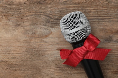Top view of microphone with red bow on wooden table, space for text. Christmas music