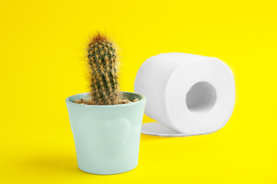 Roll of toilet paper and cactus on yellow background. Hemorrhoid problems