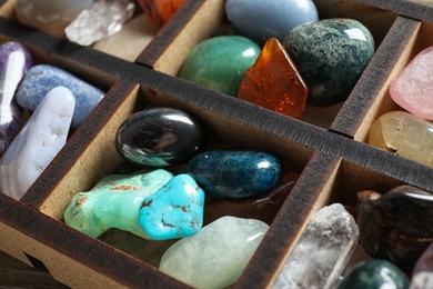 Photo of Box with different beautiful gemstones on table, closeup