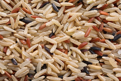 Mix of different brown rice as background, top view