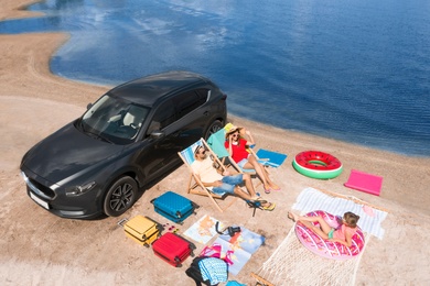 Family with beach accessories and car near river. Summer trip
