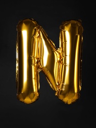 Photo of Golden letter N balloon on black background