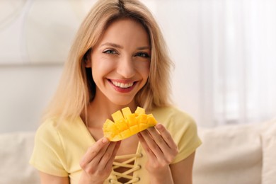 Photo of Young woman with fresh mango at home. Exotic fruit
