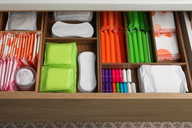 Storage of different feminine hygiene products in wooden drawer, above view
