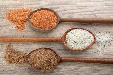 Different kinds of salt on wooden table, flat lay