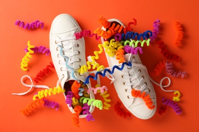 Shoes with colorful decorative spirals on orange background, flat lay. April fool's day