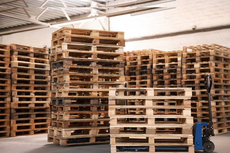Modern manual forklift and wooden pallets in warehouse