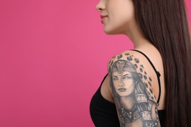 Photo of Woman with tattoos on arm against pink background, closeup. Space for text