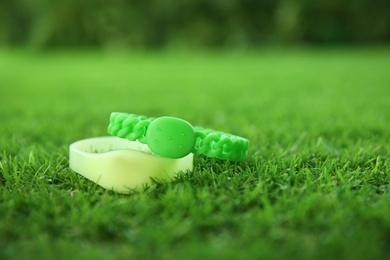 Insect repellent wrist bands on green grass. Space for text