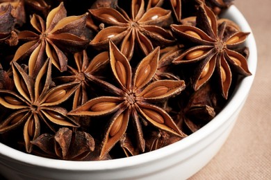 Bowl with aromatic anise stars on table, closeup