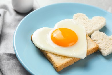 Photo of Romantic breakfast with heart shaped fried egg and toasts on table, closeup