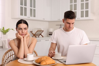 Internet addiction. Man with laptop ignoring his girlfriend in kitchen