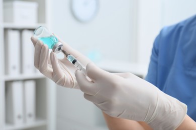 Doctor filling syringe with medication from vial in hospital, closeup
