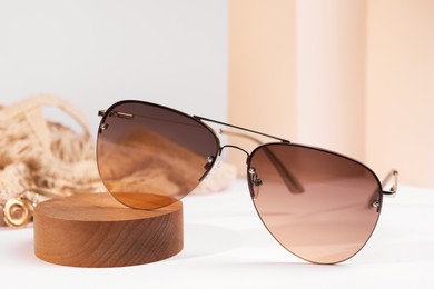 Photo of New stylish elegant sunglasses on white table, closeup