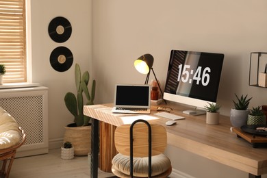 Room interior with comfortable workplace. Modern computer and laptop on wooden desk