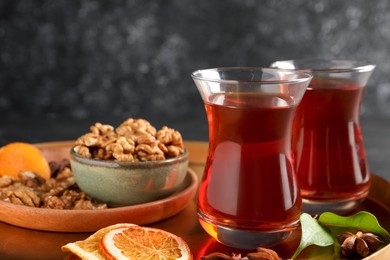 Tray with glasses of traditional Turkish tea, walnuts, dried orange and anise on table, closeup