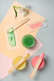 Flat lay composition with different types of wax and spatulas on color background