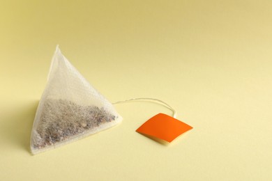 New tea bag with tab on yellow background, closeup. Space for text
