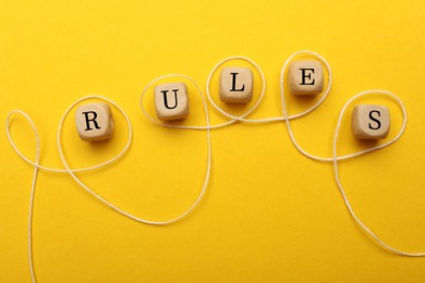 Photo of Word Rules made of wooden cubes with letters on yellow background, flat lay