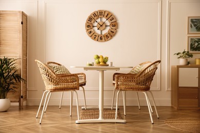 Photo of Stylish white dining table and wicker chairs in room. Interior design