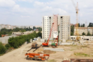 Blurred view of construction site with heavy machinery near unfinished building