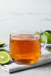Glass cup of tasty bergamot tea and fresh fruit on light grey table