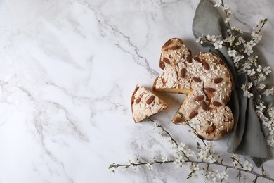 Photo of Delicious Italian Easter dove cake (traditional Colomba di Pasqua) and flowers on white marble table, flat lay. Space for text