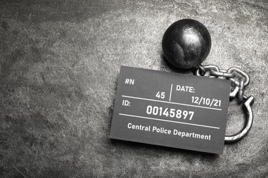 Metal ball with chain and mugshot letter board on grey table, flat lay. Space for text