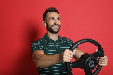 Happy man with steering wheel on red background