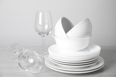 Clean plates, bowls and glasses on table against white background