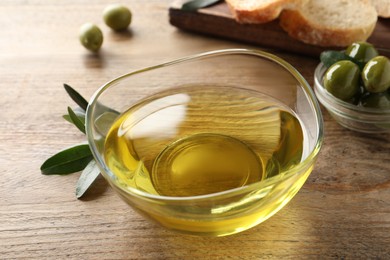 Glass bowl of olive oil on wooden table, closeup