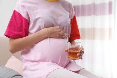 Future mother with glass of alcohol at home, closeup. Bad habits during pregnancy