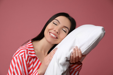 Beautiful Asian woman with pillow on dusty rose background. Bedtime