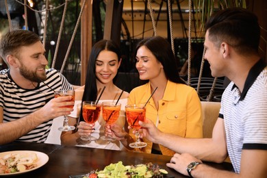 Friends with Aperol spritz cocktails resting together at restaurant