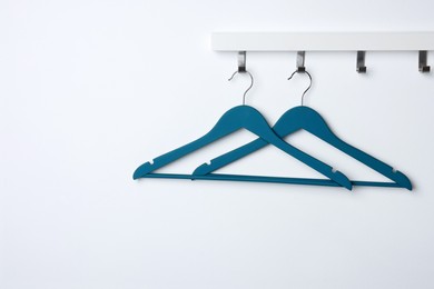 Rack with empty blue clothes hangers on white wall