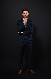 Handsome bearded man in suit on black background