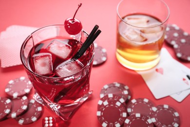 Casino chips, dice, playing cards and alcohol drinks on red table, closeup