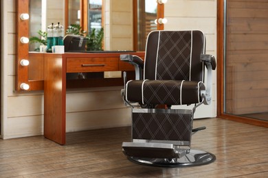 Photo of New empty chair near table with mirror in hairdressing salon