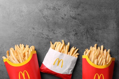 MYKOLAIV, UKRAINE - AUGUST 12, 2021: Small and big portions of McDonald's French fries on grey table, flat lay. Space for text