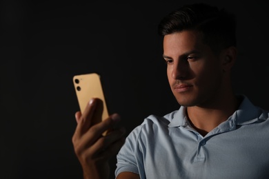 Man unlocking smartphone with facial scanner on black background. Biometric verification