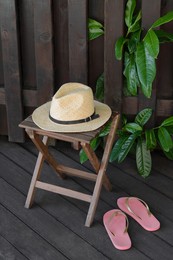 Stylish hat and flip flops near wooden fence. Beach accessories