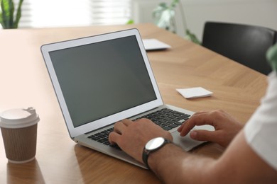 Freelancer working on laptop at table indoors, closeup