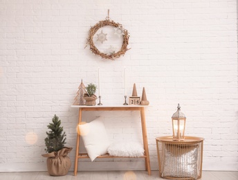Console table with Christmas decoration near brick wall. Idea for festive interior