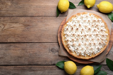 Flat lay composition with delicious lemon meringue pie on wooden table. Space for text